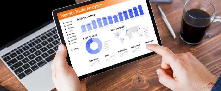 A hand holds a tablet with a website traffic analytics graph on the screen.